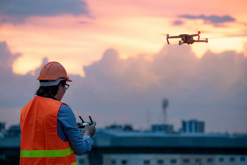 Young,Asian,Engineer,Flying,Drone,Over,Construction,Site,During,Sunset.