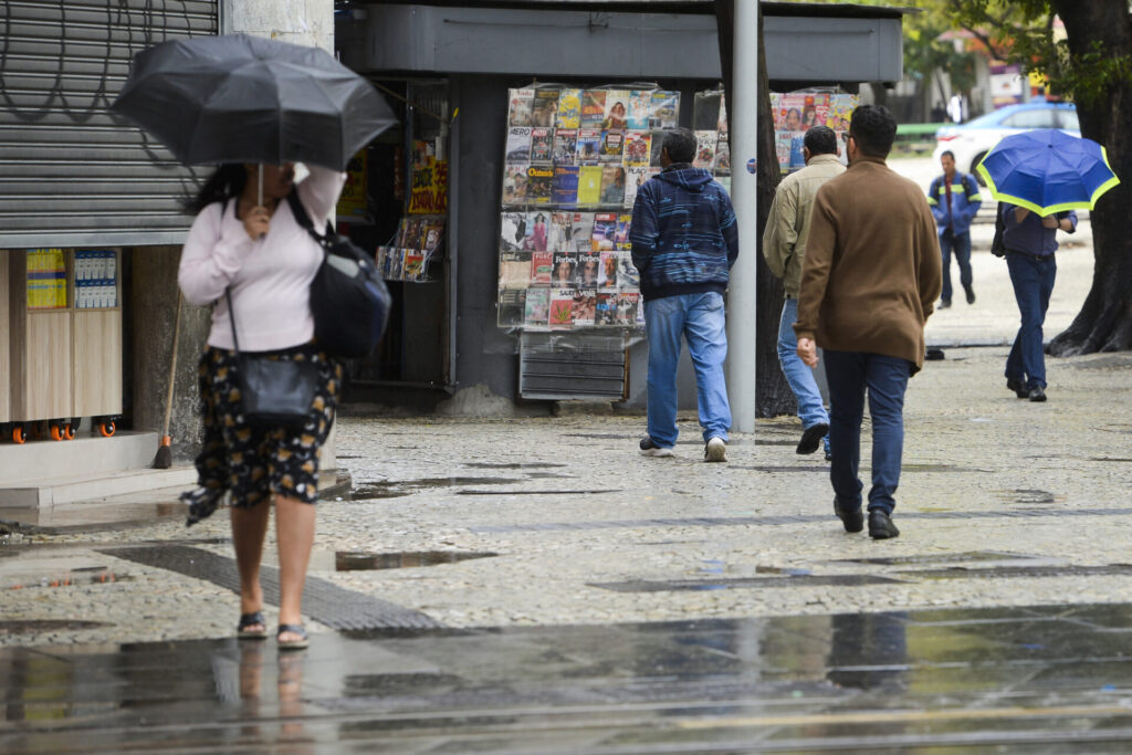 Pedestres caminham sob chuva no Rio de Janeiro durante passagem de frente fria
