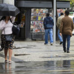 Pedestres caminham sob chuva no Rio de Janeiro durante passagem de frente fria