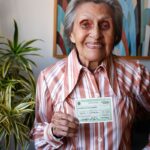Eleitora idosa mostra o título de eleitor em sua residência