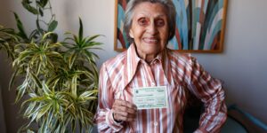 Eleitora idosa mostra o título de eleitor em sua residência