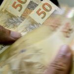 Pessoa manuseia notas de cinquenta reais