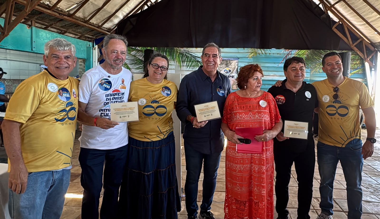 Grupo posa durante celebração de 30 anos da AEPF, com participantes segurando placas de homenagem.