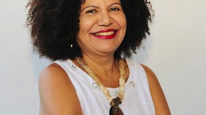 Professora Zuleide Queiroz sorrindo, com os braços cruzados