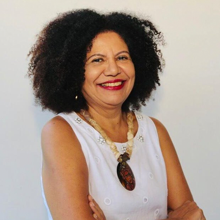 Professora Zuleide Queiroz sorrindo, com os braços cruzados